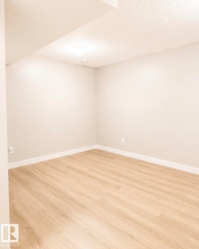 Open room featuring light wood-finish flooring, white baseboards, and neutral wall paint - 5135 1A Avenue Sw, Edmonton, AB - Indoor Photo Showing Other Room