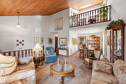 Vaulted wood-paneled ceiling with a hanging fixture, complemented by a second-story interior balcony featuring a wood railing - 4108 Ramsay Road Nw, Edmonton, AB - Indoor Photo Showing Living Room