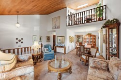 Vaulted wood-paneled ceiling with a hanging fixture, complemented by a second-story interior balcony featuring a wood railing - 
