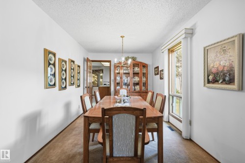 Dining area featuring a wood-finish table, chandelier lighting, and a built-in display cabinet - 4108 Ramsay Road Nw, Edmonton, AB - Indoor Photo Showing Dining Room