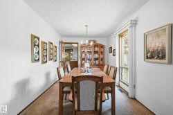 Dining area featuring a wood-finish table, chandelier lighting, and a built-in display cabinet - 