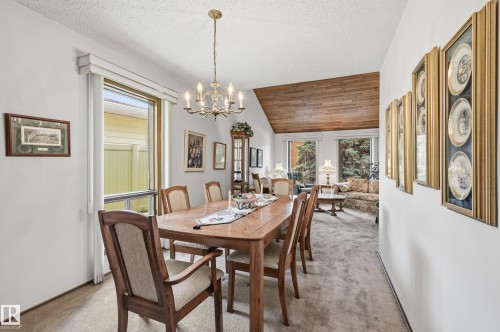 Formal dining area featuring a brass chandelier, window with privacy blinds, and light carpet flooring - 4108 Ramsay Road Nw, Edmonton, AB - Indoor Photo Showing Dining Room