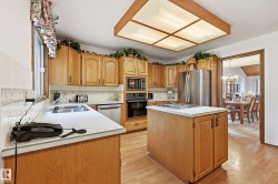 Kitchen with wood-finish flooring, light wood cabinetry, and white countertops - 