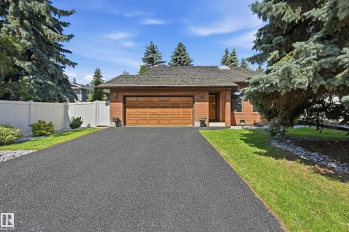 Brick exterior with an attached garage featuring a wood-panel door - 4108 Ramsay Road Nw, Edmonton, AB - Outdoor