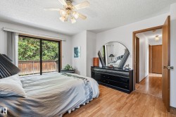 Sliding glass doors opening to an exterior balcony, light wood-finish flooring, white walls, and a ceiling fan with integrated lighting - 