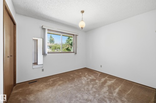 Room featuring a window with exterior tree views, neutral carpet flooring, white walls, and a ceiling-mounted light fixture - 4108 Ramsay Road Nw, Edmonton, AB - Indoor Photo Showing Other Room
