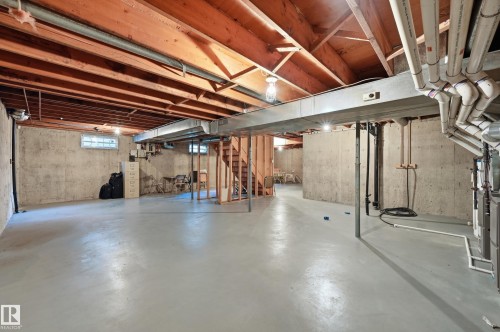 Expansive unfinished basement featuring a concrete floor, concrete walls, exposed wood ceiling joists, and a wood-frame staircase - 4108 Ramsay Road Nw, Edmonton, AB - Indoor Photo Showing Basement
