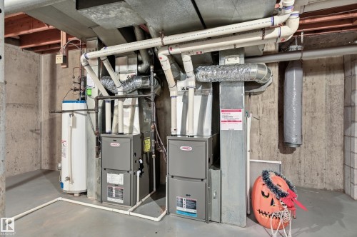 Dual furnace systems with associated ductwork and a water heater in a concrete-walled utility space - 4108 Ramsay Road Nw, Edmonton, AB - Indoor Photo Showing Basement