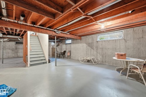 Unfinished basement featuring exposed wood ceiling joists, concrete walls, concrete flooring, and multiple window openings - 4108 Ramsay Road Nw, Edmonton, AB - Indoor Photo Showing Basement