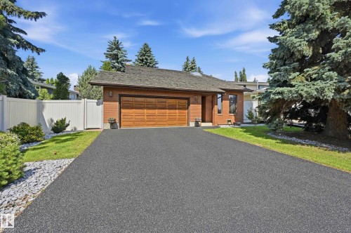Brick exterior featuring an attached double garage with a wood-panel door - 4108 Ramsay Road Nw, Edmonton, AB - Outdoor