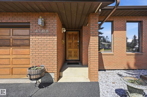 Brick exterior with an integrated garage featuring a wood-panel door - 4108 Ramsay Road Nw, Edmonton, AB - Outdoor With Exterior