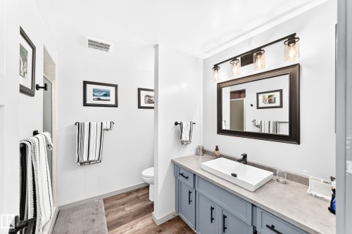 Contemporary bathroom featuring a light blue vanity with black hardware, a rectangular vessel sink, and a black-framed mirror - #401 14810 51 Av Nw, Edmonton, AB - Indoor Photo Showing Bathroom