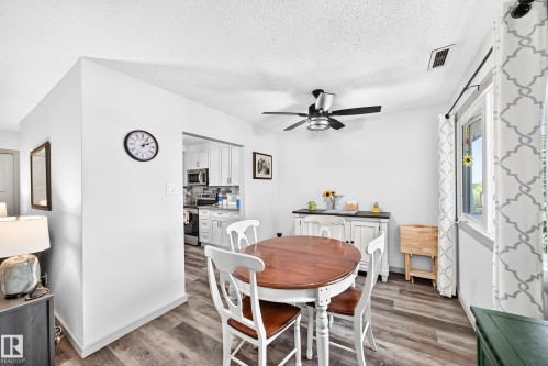 Dining area featuring wood-finish flooring, a contemporary ceiling fan, and abundant natural light from a large window - #401 14810 51 Av Nw, Edmonton, AB - Indoor Photo Showing Dining Room