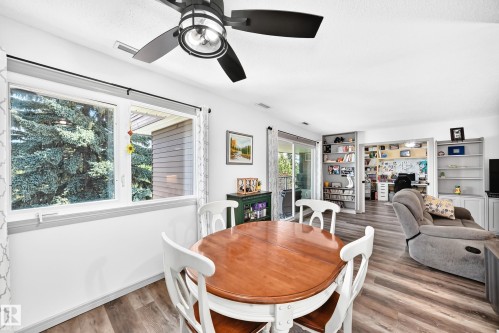 Spacious dining area featuring a contemporary ceiling fan with integrated lighting, wood-finish flooring, and white walls - #401 14810 51 Av Nw, Edmonton, AB - Indoor Photo Showing Dining Room
