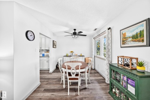Open-concept dining area featuring wood-finish flooring, a contemporary ceiling fan, and abundant natural light from multiple windows - #401 14810 51 Av Nw, Edmonton, AB - Indoor Photo Showing Dining Room