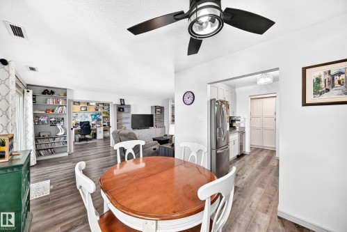 Dining area featuring wood-finish flooring, a modern ceiling fan with lighting, and an archway leading to the kitchen - #401 14810 51 Av Nw, Edmonton, AB - Indoor Photo Showing Dining Room