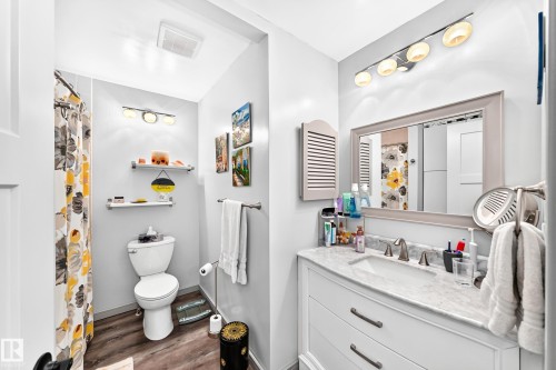 Bathroom featuring a white vanity with a stone countertop, an undermount sink, and brushed nickel fixtures - #401 14810 51 Av Nw, Edmonton, AB - Indoor Photo Showing Bathroom