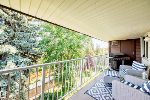 Covered balcony featuring white railing, concrete flooring, and a brown shiplap wall - #401 14810 51 Av Nw, Edmonton, AB - Outdoor With Balcony With Exterior