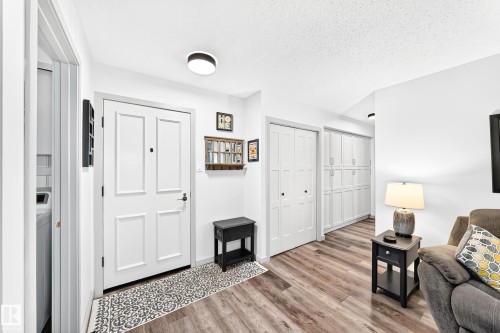 Entryway featuring wood-finish flooring, white paneled doors, and ceiling-mounted lighting - #401 14810 51 Av Nw, Edmonton, AB - Indoor