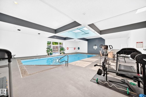 Indoor swimming pool with integrated fitness area, skylight, and large exterior windows - #401 14810 51 Av Nw, Edmonton, AB -  Photo Showing Other Room With In Ground Pool
