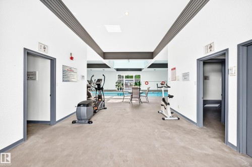 Indoor pool area featuring a skylight, concrete-finish flooring, and direct access to changing rooms - #401 14810 51 Av Nw, Edmonton, AB - Indoor With In Ground Pool