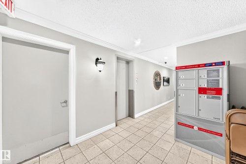 Well-lit corridor featuring neutral wall tones, decorative sconce lighting, and a durable tile floor - #401 14810 51 Av Nw, Edmonton, AB - Indoor