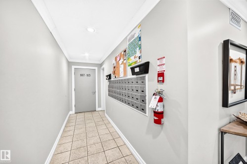 Corridor featuring light-toned tile flooring, neutral wall finishes, crown molding, and recessed lighting - #401 14810 51 Av Nw, Edmonton, AB - Indoor Photo Showing Other Room