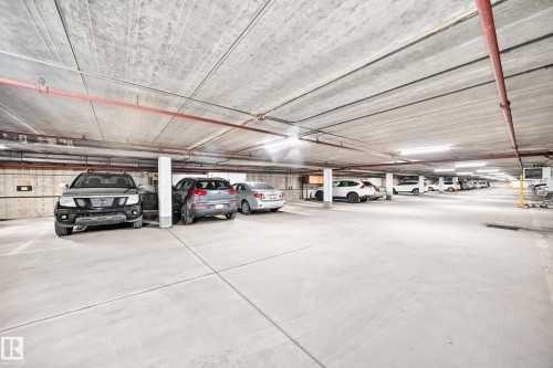 Underground parking facility featuring concrete flooring and ceiling - #401 14810 51 Av Nw, Edmonton, AB - Indoor Photo Showing Garage