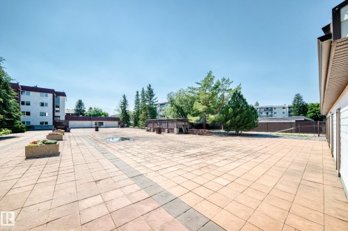Expansive paved patio area featuring a uniform pattern of light-toned pavers with darker accent strips - #401 14810 51 Av Nw, Edmonton, AB - Outdoor