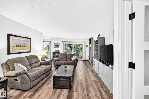 Bright interior space featuring wood-finish flooring, white walls, and a white ceiling - #401 14810 51 Av Nw, Edmonton, AB - Indoor Photo Showing Living Room