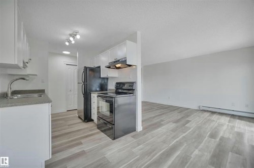 Modern kitchen featuring white cabinetry, gray countertops, stainless steel appliances, and wood-finish flooring - #10 4616 47 St, Leduc, AB - Indoor Photo Showing Kitchen With Double Sink