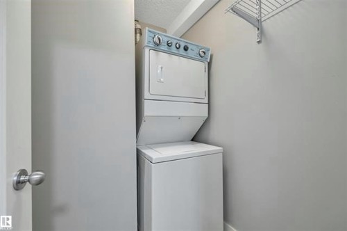 Dedicated laundry area featuring a white stacked washer and dryer unit, complemented by neutral wall tones and a wall-mounted wire shelf - #10 4616 47 St, Leduc, AB - Indoor Photo Showing Laundry Room