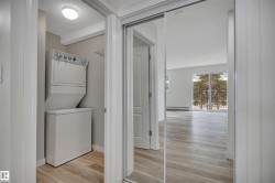 Dedicated laundry closet featuring a stackable washer and dryer, complemented by wood-finish flooring - 