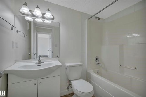 Bathroom featuring a vanity with integrated sink, chrome faucet, and mirrored cabinet - #10 4616 47 St, Leduc, AB - Indoor Photo Showing Bathroom