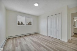 Spacious room featuring light-tone wood-finish flooring, white walls, and a large window - 