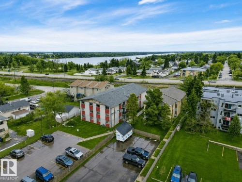 Multi-story residential building with red and white exterior siding and a pitched roof - #10 4616 47 St, Leduc, AB - Outdoor With Body Of Water With View