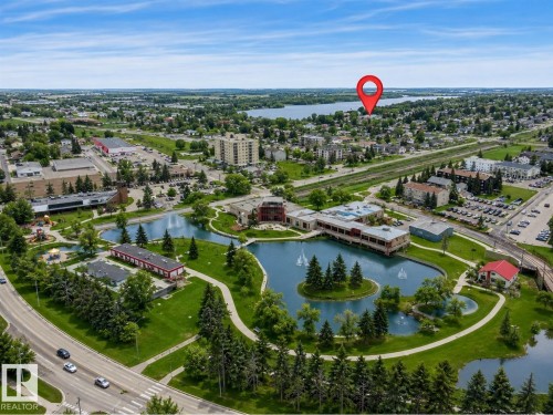 Aerial perspective featuring a central park with multiple water features, mature evergreen trees, and green spaces - #10 4616 47 St, Leduc, AB - Outdoor With Body Of Water With View