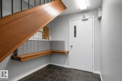 Entryway featuring a wood staircase with black iron balusters, a white door with a rectangular window, and dark tile flooring - 