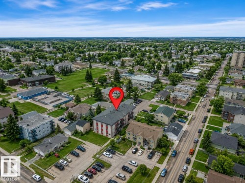 Aerial view showcasing a multi-story building with a red and gray facade, situated within a developed urban area - #10 4616 47 St, Leduc, AB - Outdoor With View