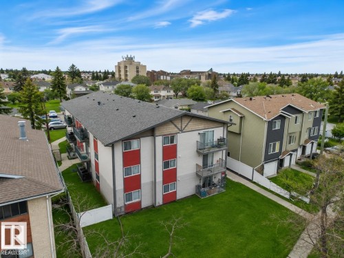 Multi-story building featuring balconies with glass railings, a grey shingle roof, and a red and white facade - #10 4616 47 St, Leduc, AB - Outdoor
