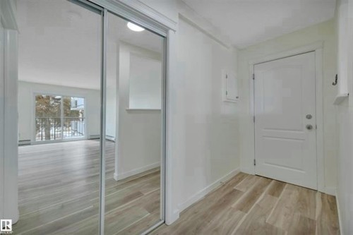 Entryway featuring wood-look flooring and a mirrored closet - #10 4616 47 St, Leduc, AB - Indoor Photo Showing Other Room