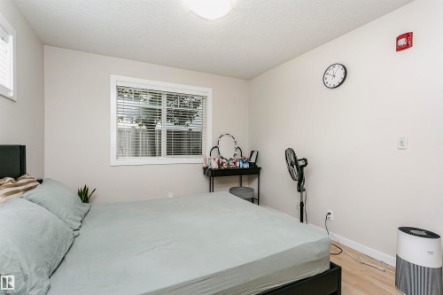 Windowed room featuring light-toned wall paint and wood-finish flooring - #104 9519 160 Av Nw, Edmonton, AB - Indoor Photo Showing Bedroom