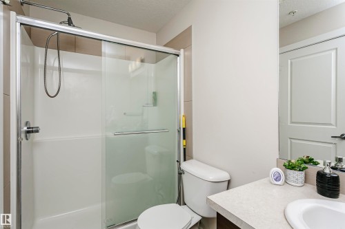 Shower enclosure with clear glass sliding doors and an integrated showerhead - #104 9519 160 Av Nw, Edmonton, AB - Indoor Photo Showing Bathroom