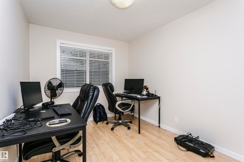 Interior room with wood-finish flooring, light-colored walls, and a window with horizontal blinds - #104 9519 160 Av Nw, Edmonton, AB - Indoor Photo Showing Office