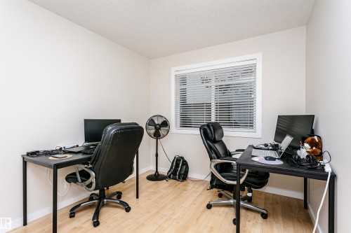 Room featuring neutral wall paint, wood-finish flooring, and a window with horizontal blinds - #104 9519 160 Av Nw, Edmonton, AB - Indoor Photo Showing Office