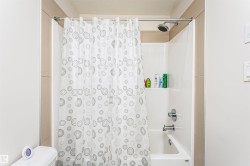 Shower/tub combination with a white acrylic surround, chrome fixtures, and a rain-style showerhead - 