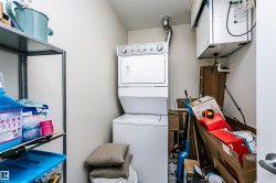 Dedicated utility space featuring a stacked washer and dryer unit, overhead ventilation system, and a metal shelving unit - 