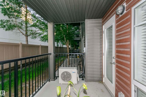 Private outdoor patio featuring a concrete surface and black metal railing - #104 9519 160 Av Nw, Edmonton, AB - Outdoor With Exterior