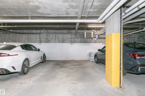 Underground parking space featuring concrete flooring and exposed ceiling utilities - #104 9519 160 Av Nw, Edmonton, AB - Indoor Photo Showing Garage