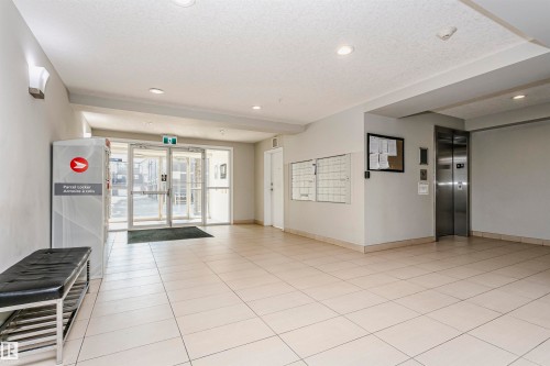 Lobby entrance featuring large format tile flooring, recessed lighting, double glass entry doors, and a built-in elevator - #104 9519 160 Av Nw, Edmonton, AB - Indoor Photo Showing Other Room